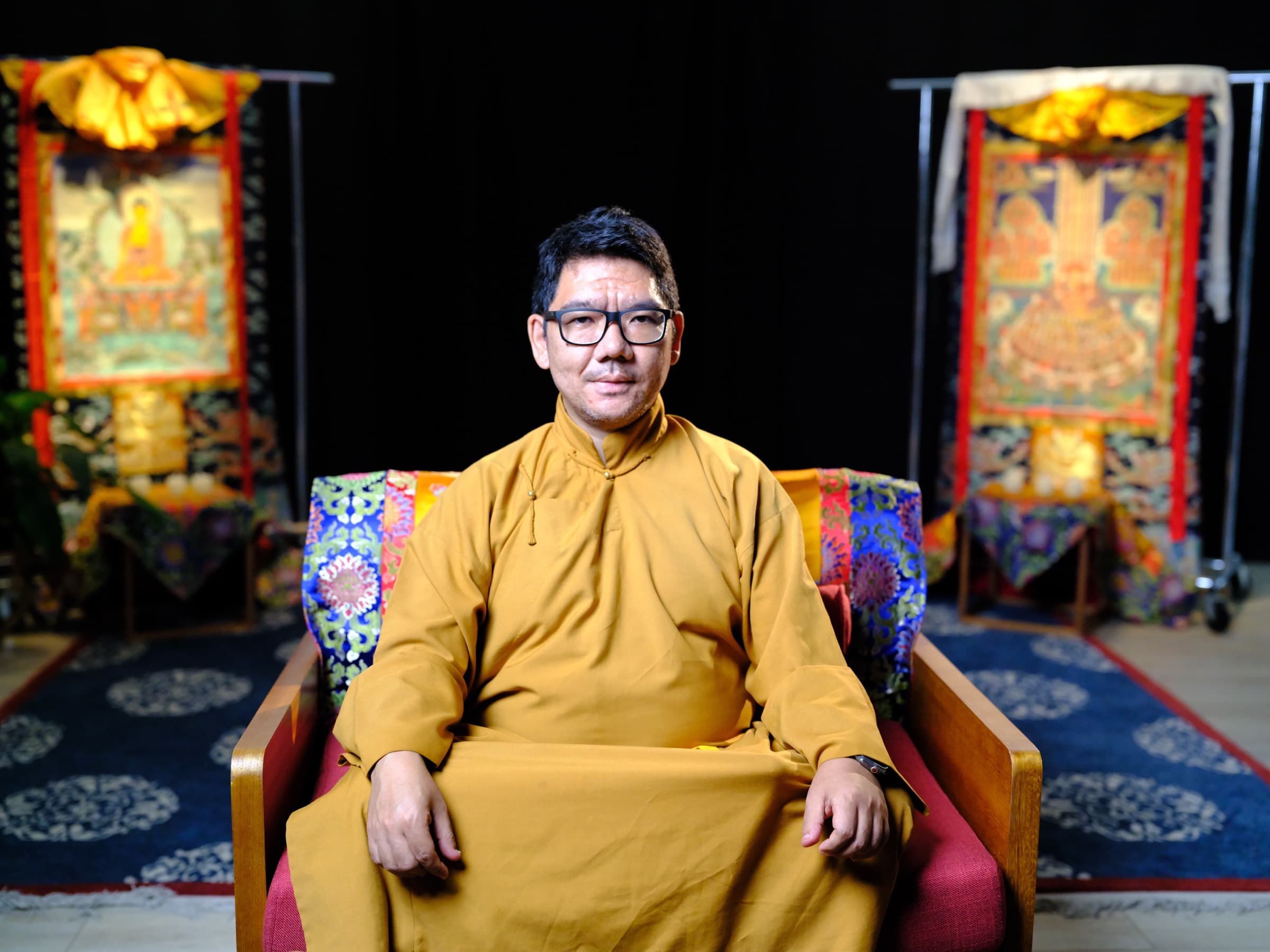 H.E Serkong Tsenshap Rinpoche seated before thangkas
